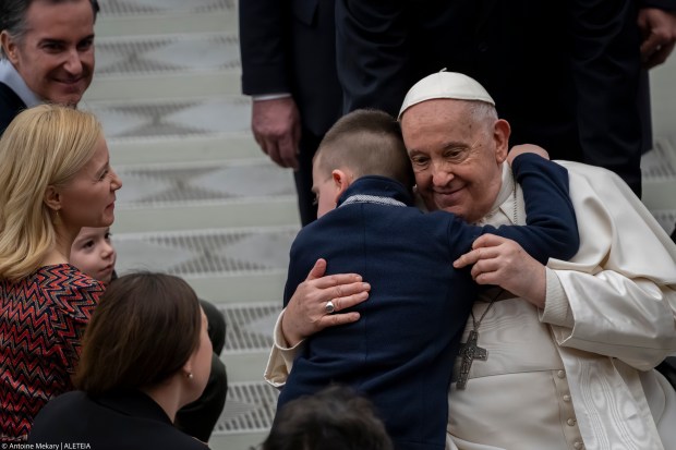 A kid hugs Pope Francis at the end of his weekly general audience
