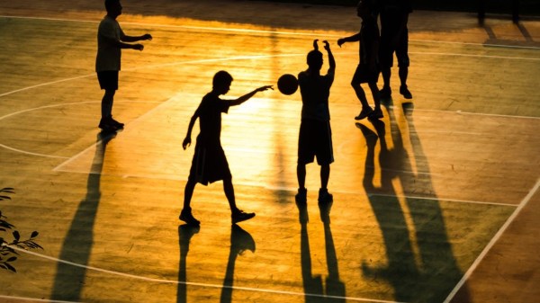 Boys playing basketball at dusk