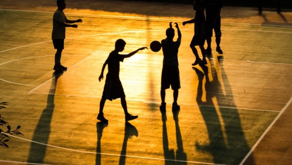 Boys playing basketball at dusk