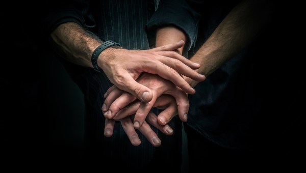 Grupa młodych ludzi ustawia dłonie jedne na drugich