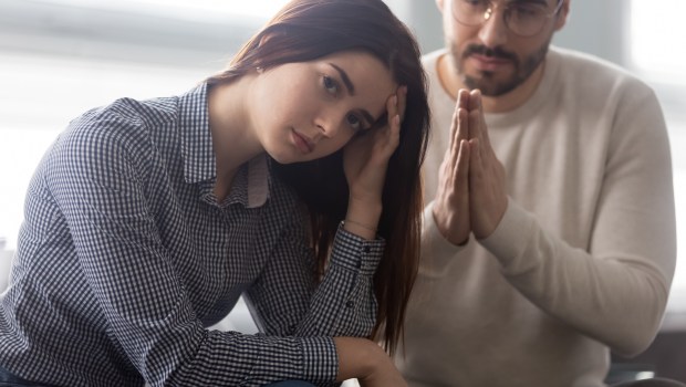 Mąż składa swoje ręce w geście prośby i błaga o coś żonę