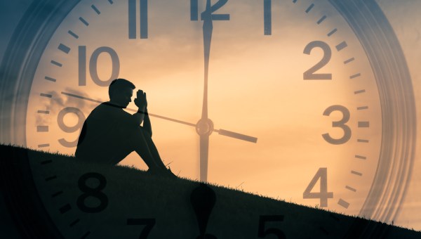 Mężczyzna modli się na tle zegara