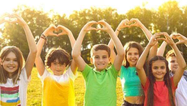 Radosne dzieci układają serca z dłoni