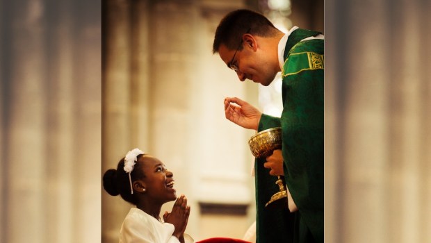 Dziewięciolatka przyjmuje komunię świętą i szczerze się uśmiecha