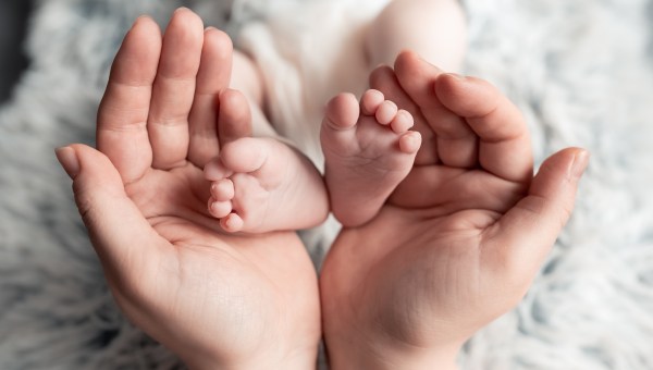 Kobieta trzymająca stópki dziecka w dłoniach