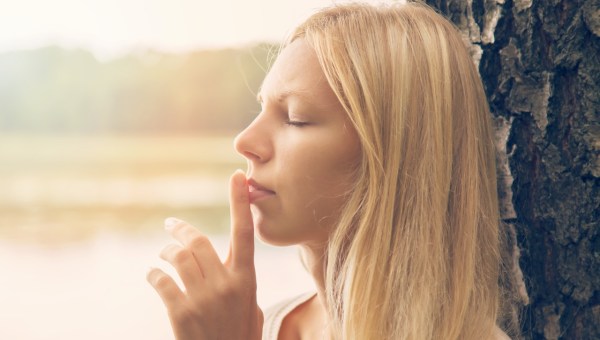 Piękna kobieta z zamkniętymi oczami przykłada palec do ust