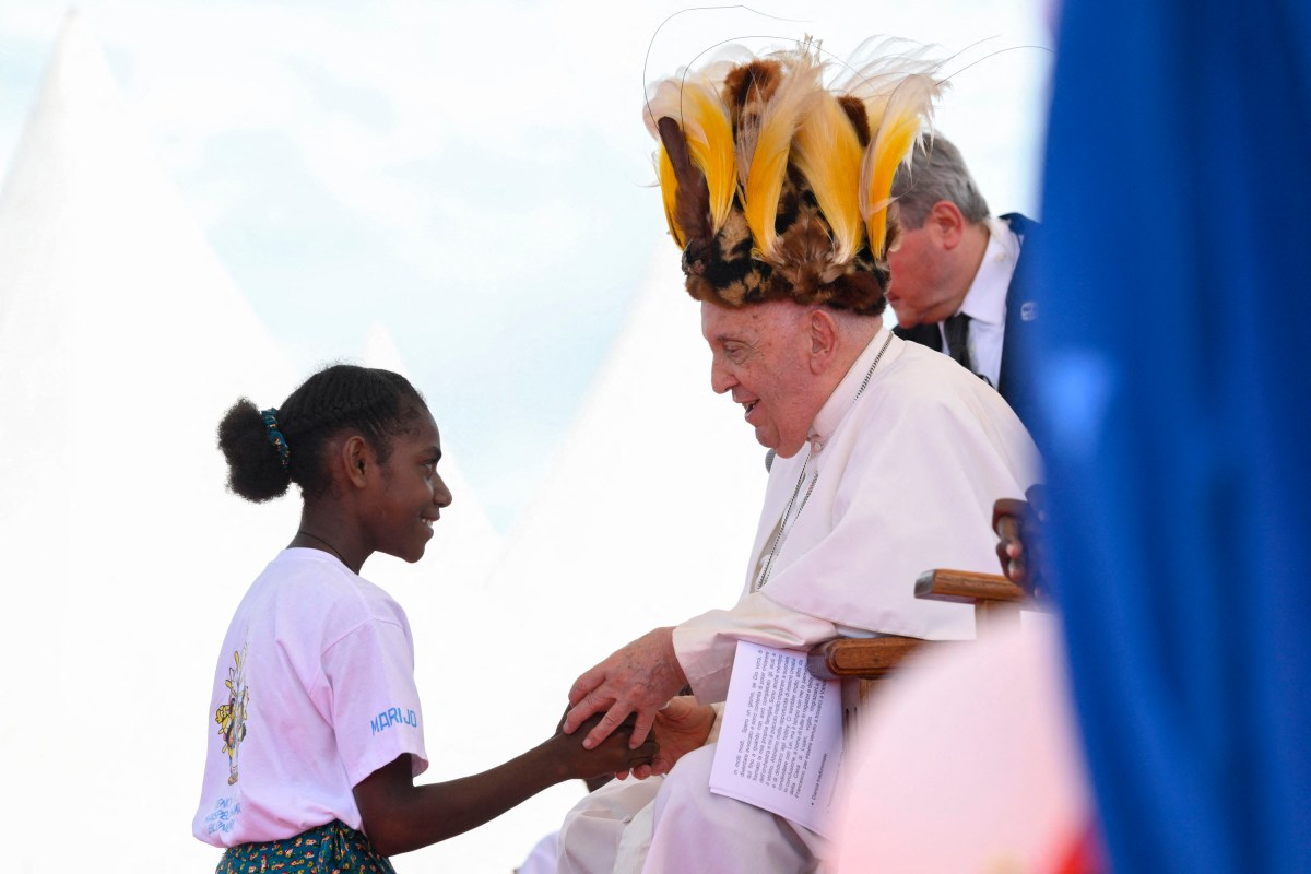 Pope Francis, seen wearing a traditional headdress, interacting with a youth during a meeting with Catholic faithful of the diocese of Vanimo in front of Holy Cross Cathedral in Vanimo, Papua New Guinea, on September 8, 2024