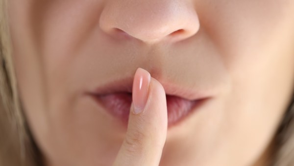 Kobieta w geście uciszania przykłada palec do ust