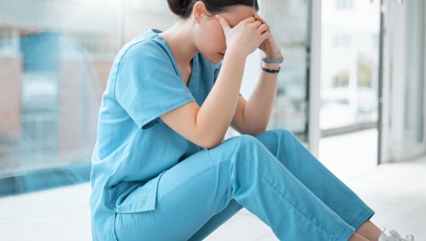 Smutna pielęgniarka siedzi i zakrywa swoją twarz
