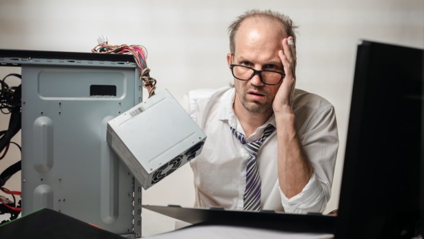 Zmęczony mężczyzna przy zepsutym komputerze