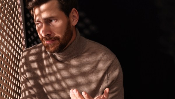 Man talking to priest during confession in booth, space for text