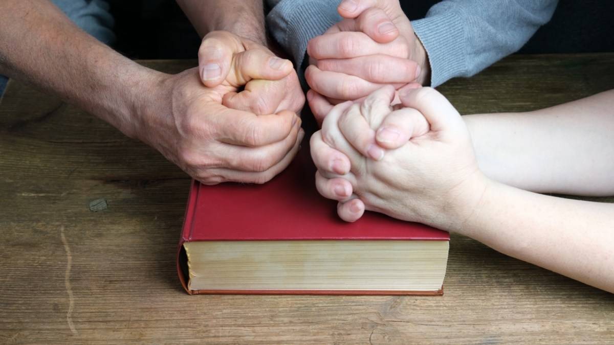 Dłonie ludzi złożone na Biblii