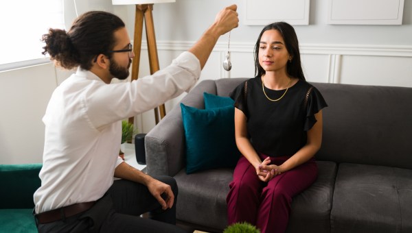 Thérapeute hispanique masculine essayant une technique d'hypnose pour traiter une patiente avec sa dépression et son anxiété