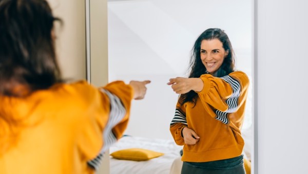 Radosna kobieta patrzy w lustro i wskazuje na siebie