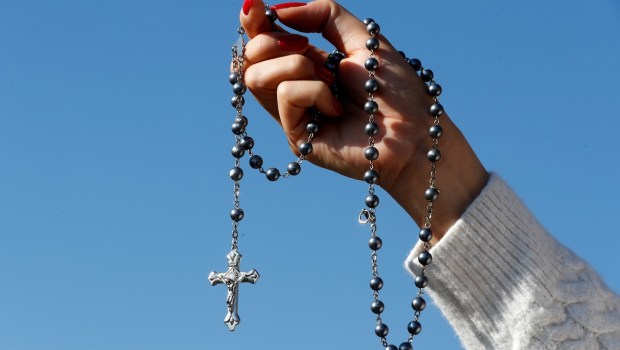woman-hand-rosary-blue-sky