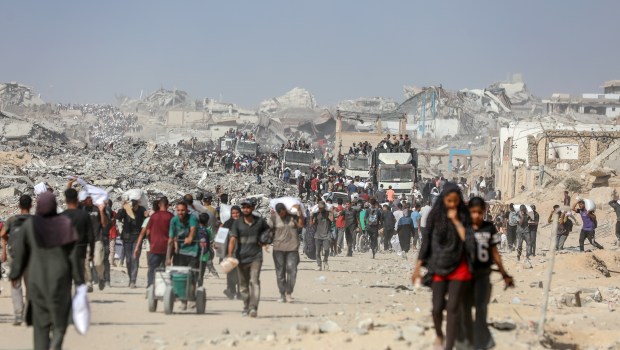 Palestinians carry flour and food aid they received at the Zikim crossing in the central Gaza Strip, August 8, 2025